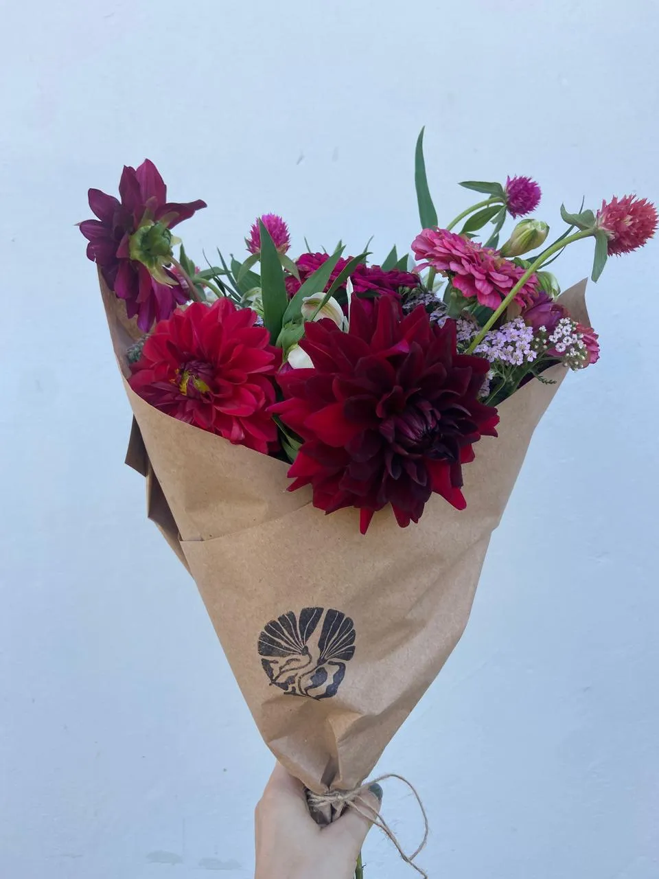 Deep burgundy dahlias and zinnias in kraft paper